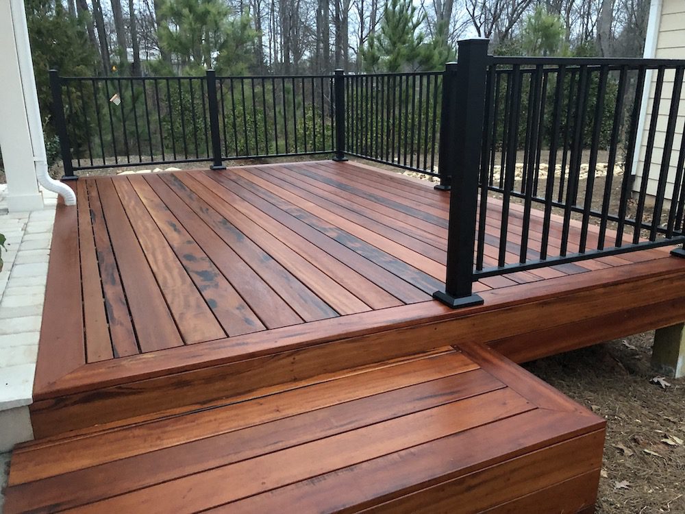 Hard wood deck with black railing with a view of trees