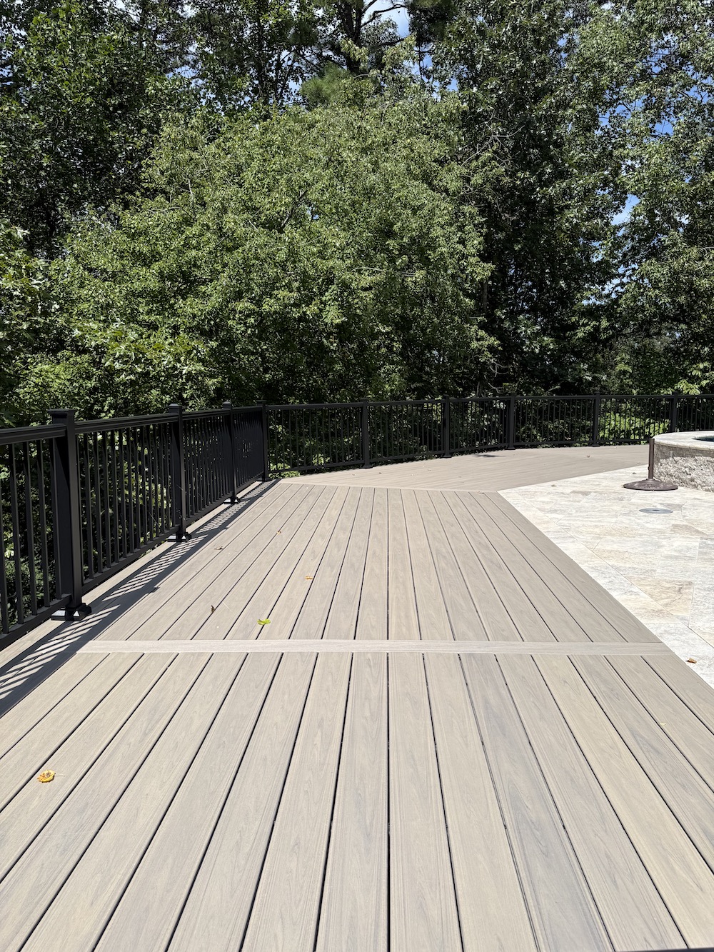 Long composite deck with black railing and overlooking trees view